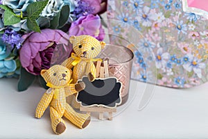 Cute beautiful decor, a small black Board for notes, two yellow textile bears and a bouquet of flowers in a vase