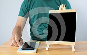 Small black board on wooden table,blank blackboard  and man with smartphone