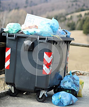 small black dumpster and many garbage bags