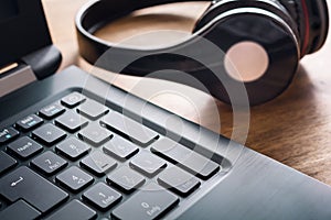 Small Black Wireless Overhead Headphone Lying Next To A The Keyboard Of A Notebook