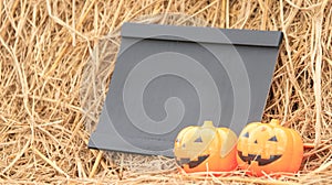 Small blackboard and artificial pumpkins on rice straws with copyspace