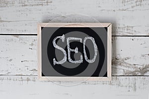 Small blackboard with handwritten text SEO on gray wooden background
