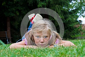 Small blonde girl child with ponytail lay in grass enjoying summ