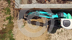 A small blue excavator works near the building. bird`s eye view.