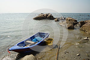 A small blue fishing boat moored on the beach.