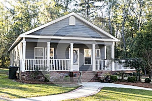 Small blue gray mobile home with a front and side porch with white railing