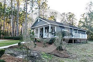 Small blue gray mobile home with a front and side porch with white railing