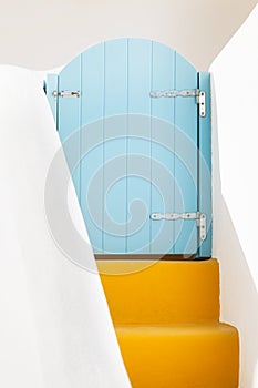 Small blue greek door and yellow steps on Santorini island, Greece