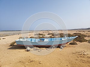 Small blue skiff in desert next to Red Sea