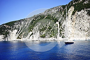 Small boat on azure sea with beautiful beach on coast of Ithaka island, Greece