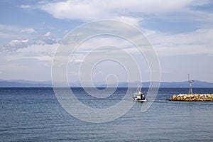 Small boat in blue sea approaching the harbor