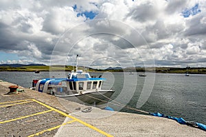 Small boat docked in the harbor and boats in the middle of the bay on Inishbofin Island photo