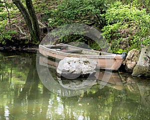 Small boat floating in a green pond of water