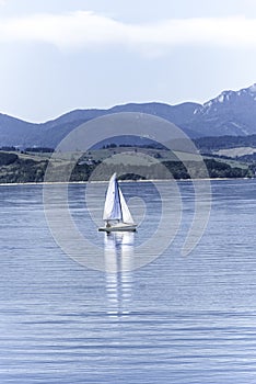 Small boat floating on a lake and mountains in the background