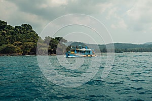 A small boat glides on a calm blue sea, leaving a gentle trail behind on a bright summer day