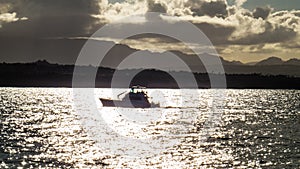 Small boat going slowly over the golden water