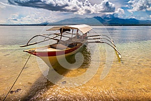 Small boat on the green ocean with mountains in the background, Maluku, Indonesia photo