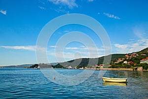 A small boat is moored near the shore beside the road around the Bay of Kotor at Durici in Montenegro