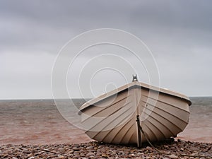 Small boat on pebble beach, aground. Winter.