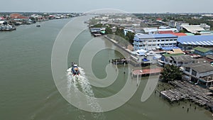 A small boat sails on a river between houses