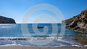 Small boat on the sea, blue clear sky, calm sea water and sandy beach background