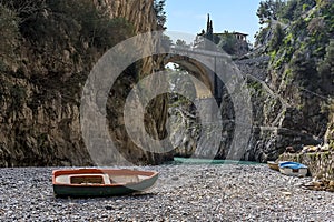 A small boat stands adrift on the shingle beach of Fiordo di Furore on the Amalfi coast, Italy photo