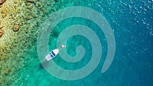 Small boat on turquoise sea water near a rocky shoreline