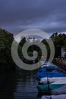 Small boats in canal at night with cloudy sky and raincovers