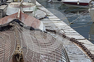 Small boats covered with a fishing net in a marina on the coast