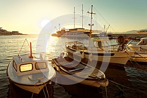 Small boats and a sailboat moored in the harbor of a town Postira - Croatia, island Brac