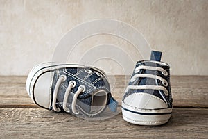 Small boots on a wooden floor, baby`s first steps, cute sneakers for a baby - a symbol of motherhood and a happy family, baby`s bi