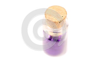 Small bottle container with purple nail color inside and cork top on white surface