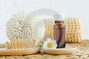 Small bottle with essential chamomile oil, wooden hairbrush and chamomile flower. Aromatherapy, homemade beauty treatment