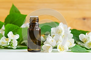 Small bottle with essential oil and mock orange (jasmine) flowers. Aromatherapy, merbal medicine concept.