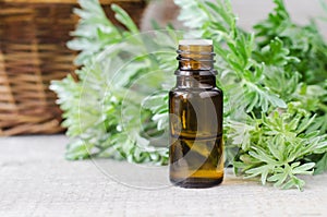 Small bottle with essential wormwood oil (extract, tincture). Old wooden background. Aromatherapy, spa and herbal