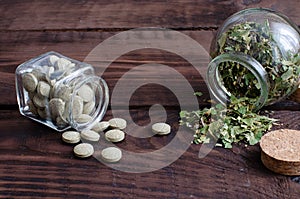 Small bottle with herbal pills and phial with medicinal herbs