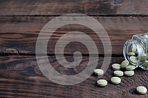 Small bottle with herbal pills on wooden background with copy space