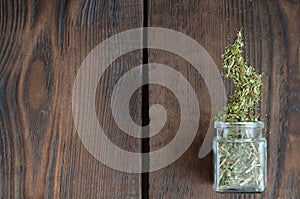 Small bottle with medicinal herbs on wooden background with copy space