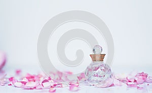 Small bottle of perfume with pink petals