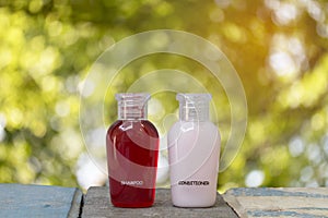 Small bottle of shampoo and conditioner with abstract nature bokeh blur