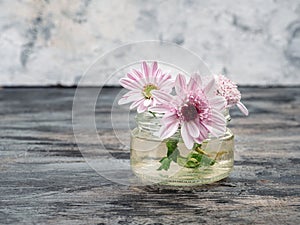 A small bouquet of pink chrysanthemums in a glass jar