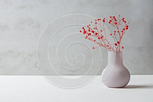 Small Bouquet of Red Flowers in Vintage Vase on White Table Grey Cement Wall Background. Styled Stock Image Mockup for Text Art