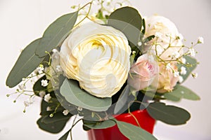 a small bouquet of white roses in a red vase. Flowers for birthday, wedding, Valentine's Day