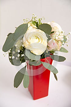 a small bouquet of white roses in a red vase. Flowers for birthday, wedding, Valentine's Day