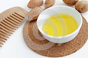 Small bowl with almond oil and wooden hair comb for natural hair