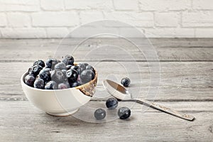 Small bowl of black blueberries with spoon next to it, placed on