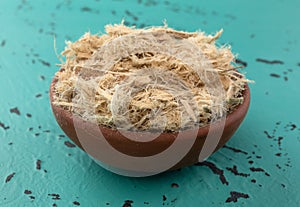 Small bowl filled with shredded slippery elm bark on a tabletop side view photo