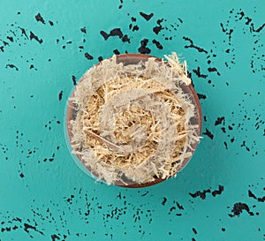 Small bowl filled with shredded slippery elm bark on a tabletop top view