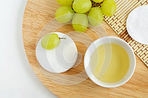 Small bowl with grape seed oil grape juice, vinegar, cotton pads. Ingredients for preparing homemade hair mask, face toner.