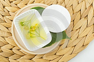 Small bowl with homemade linden (tilia, basswood, lime tree) face toner with linden flowers and cotton pad.